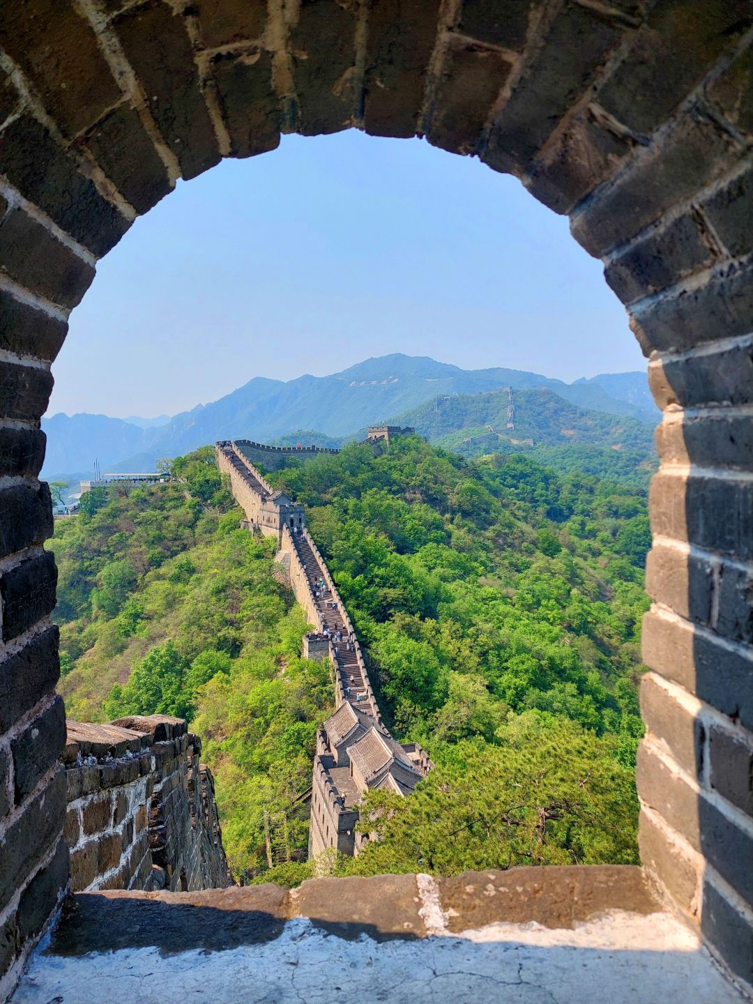 Zu sehen ist die Chinesische Mauer aus dem Blickwinkel eines Torbogens in der Mauer.
